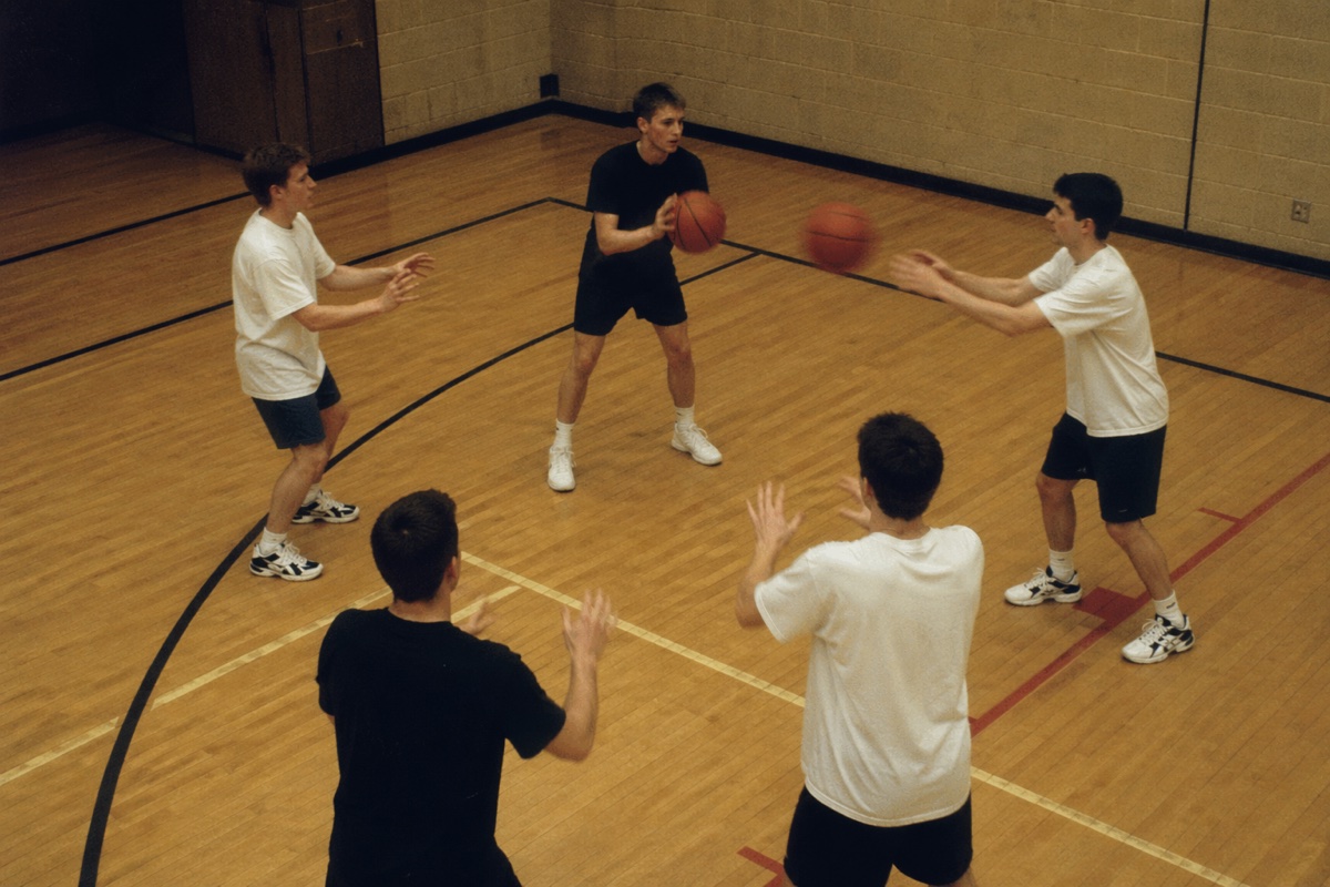 体育館でバスケットボールを回す5人の人物