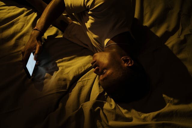 暗い部屋でスマートフォンの光に照らされる人