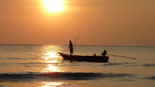 夕暮れの海で漁をする漁船のシルエット
